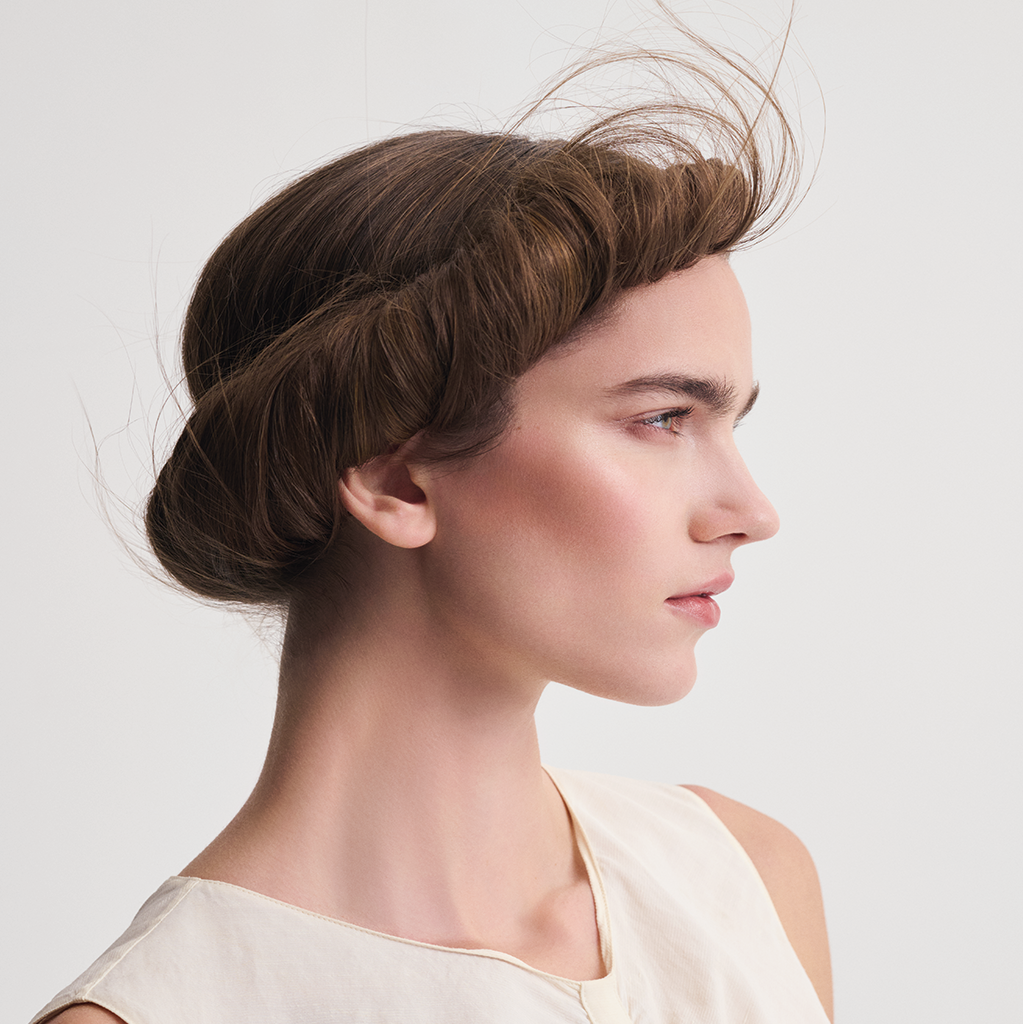 Frau mit elegant hochgestecktem braunem Haar und gepflegtem Styling